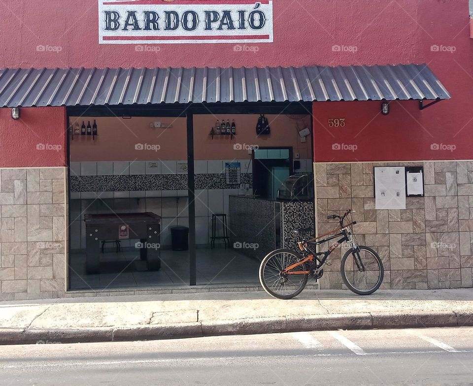 A bicycle by a traditional bar, near an obituary wall