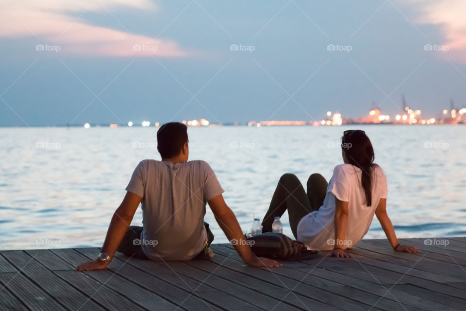 Couple Sitting At The Dock Talking And Enjoying The Night View
