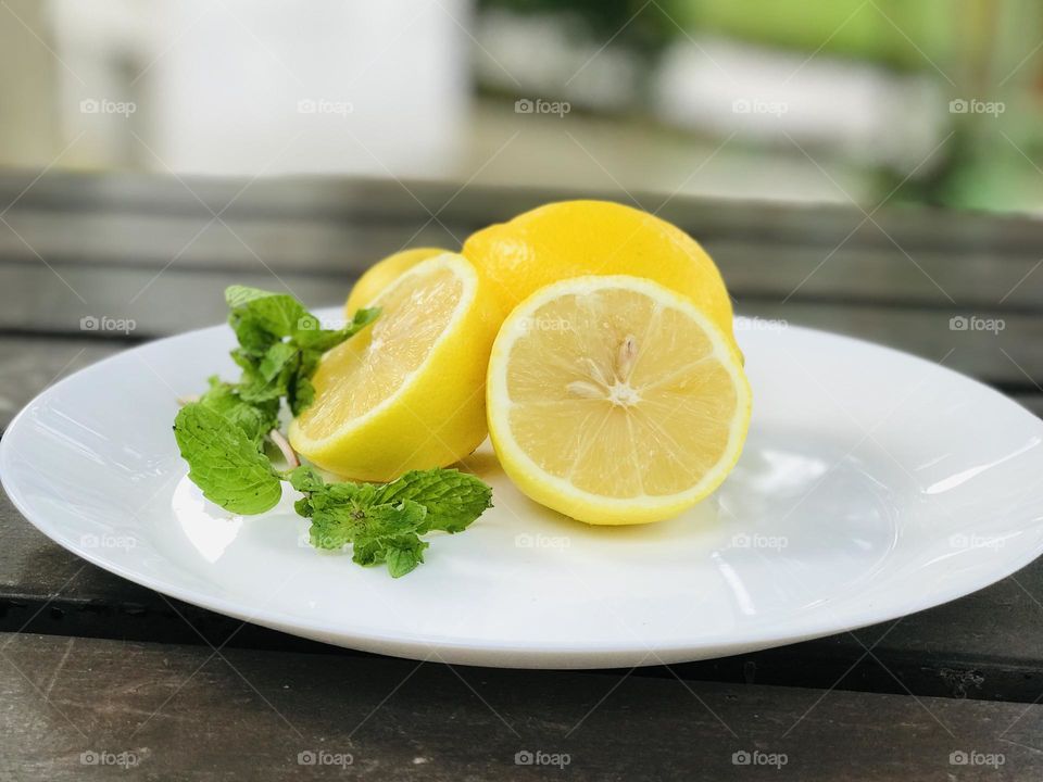 A plate with sliced lemon and mint leaves.