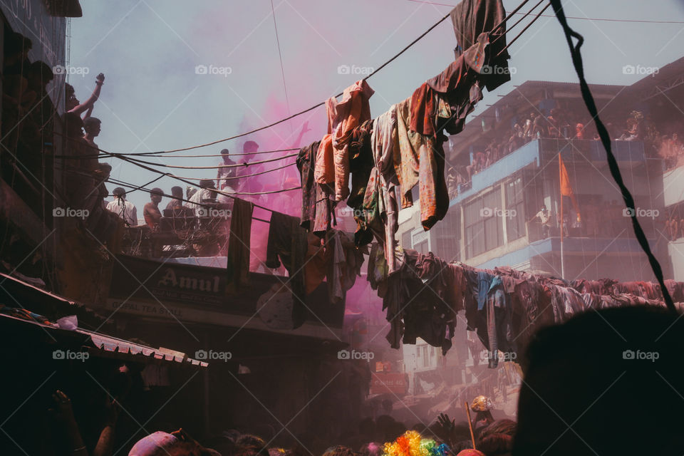 People throw clothes and pink powder in a crowded square during Holi festival in Pushkar, India.