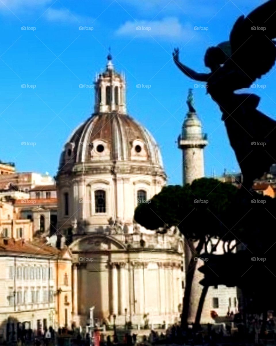 Santa Maria di Loreta. In the foreground is a bronze statue of an angel on the Victorian altar of Victor Emmanuel's fatherland. Rome