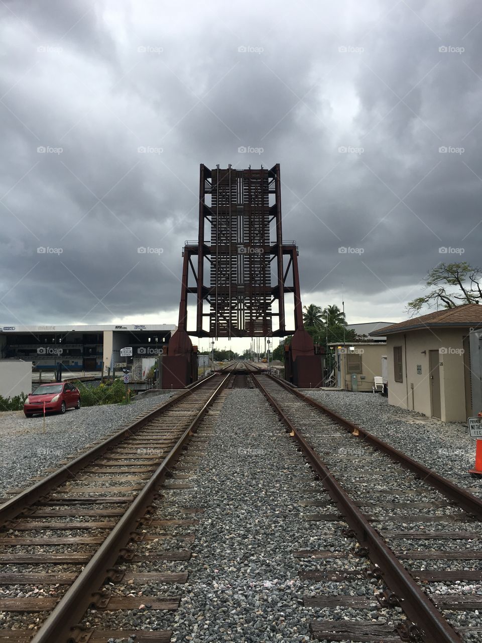 Perspective shot as storm clouds gather above an old, rusting railway drawbridge crossing a canal