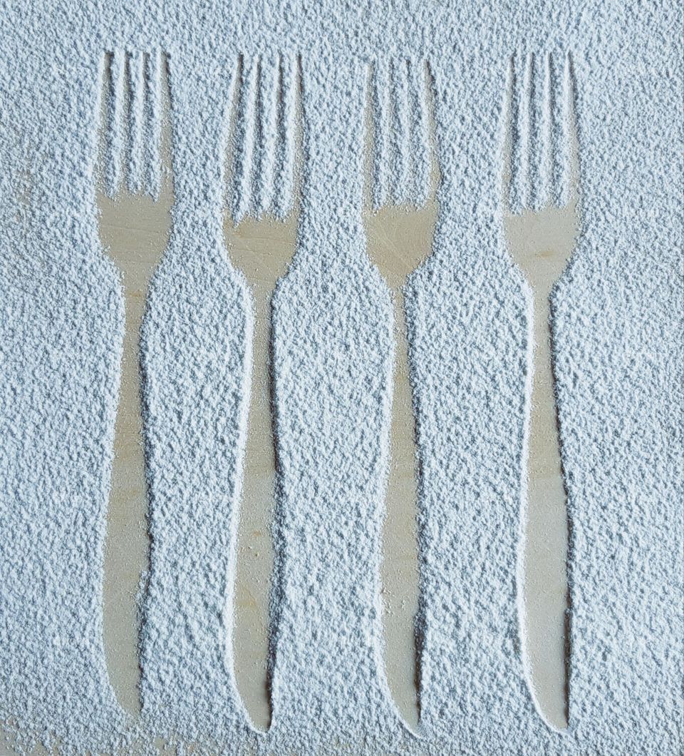 Silhouette of forks drawing with white flour on wooden background