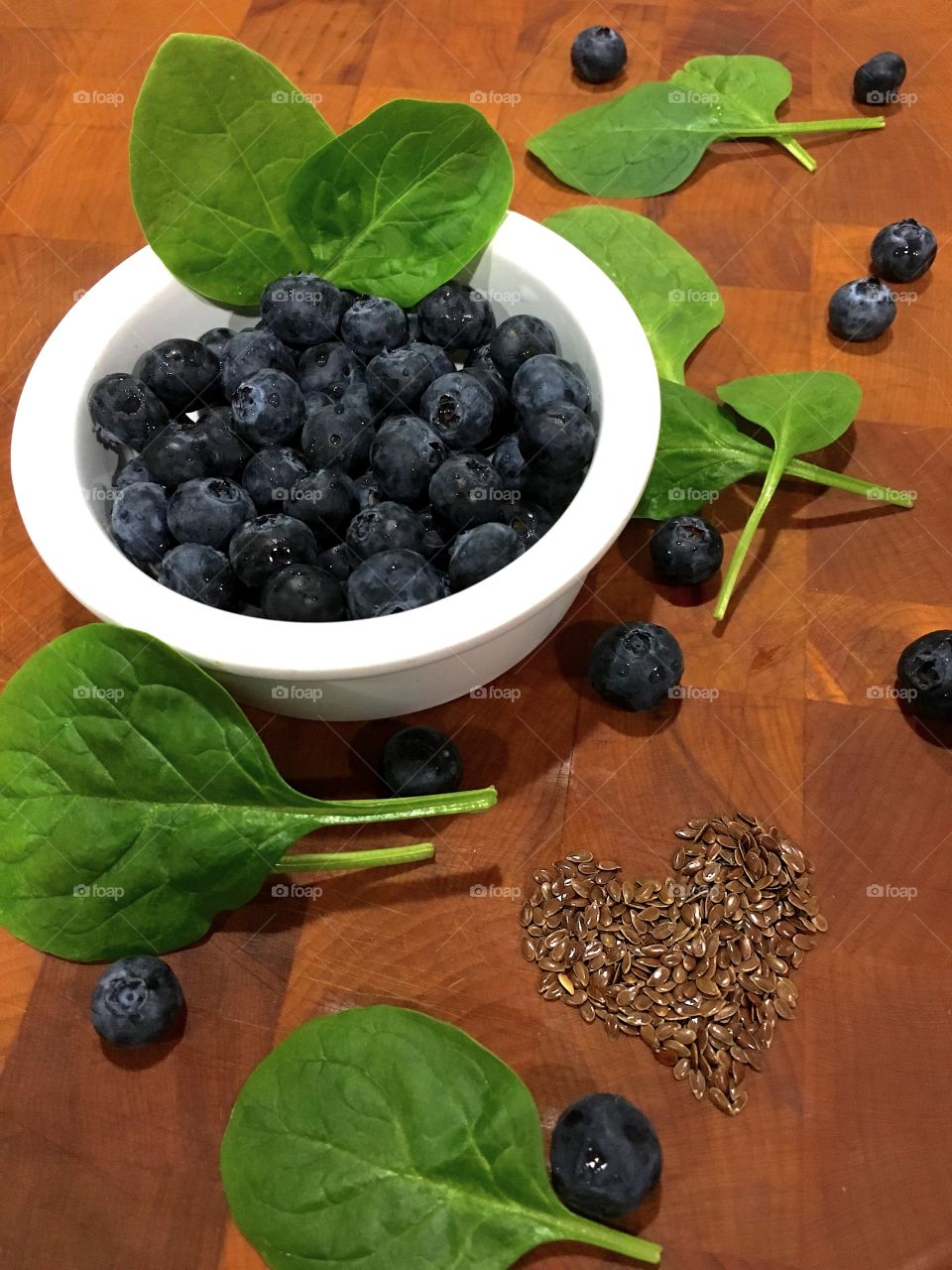 Flax seed in heart shape, with blueberries and spinach leaf