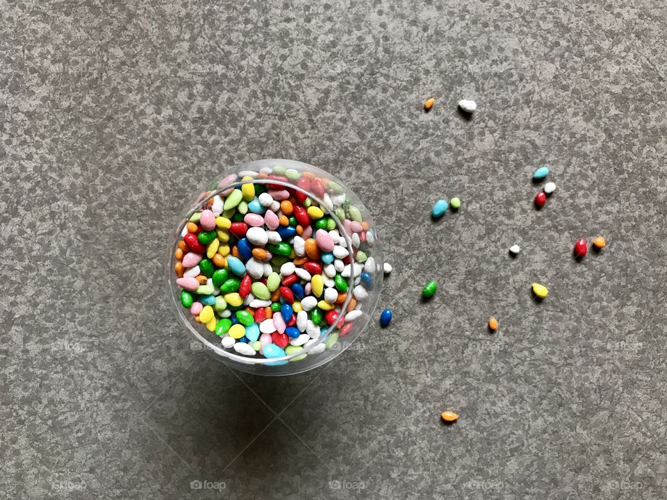 Small candies in a glass from above on grey  