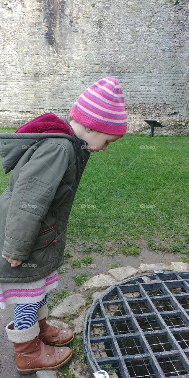child looking down deep well in old castle