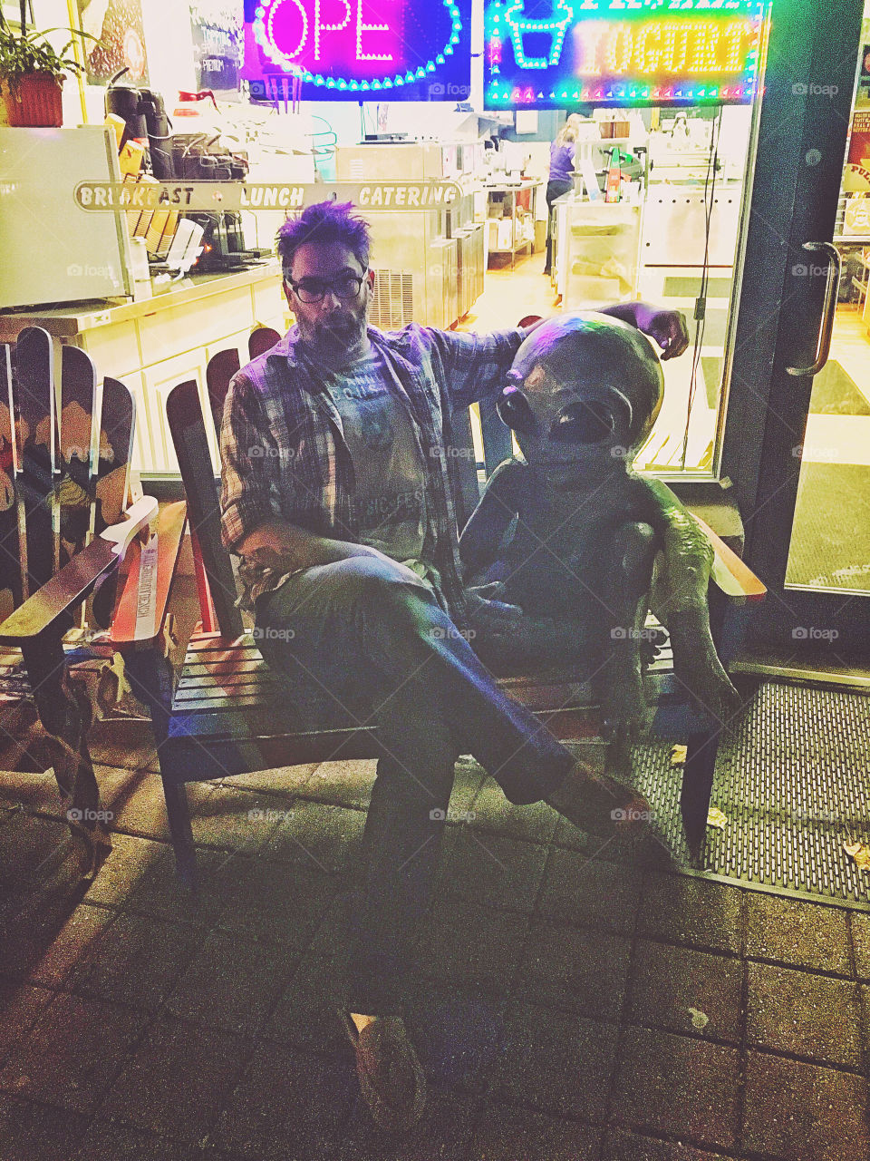 Portrait of a man sitting on bench with alien statue