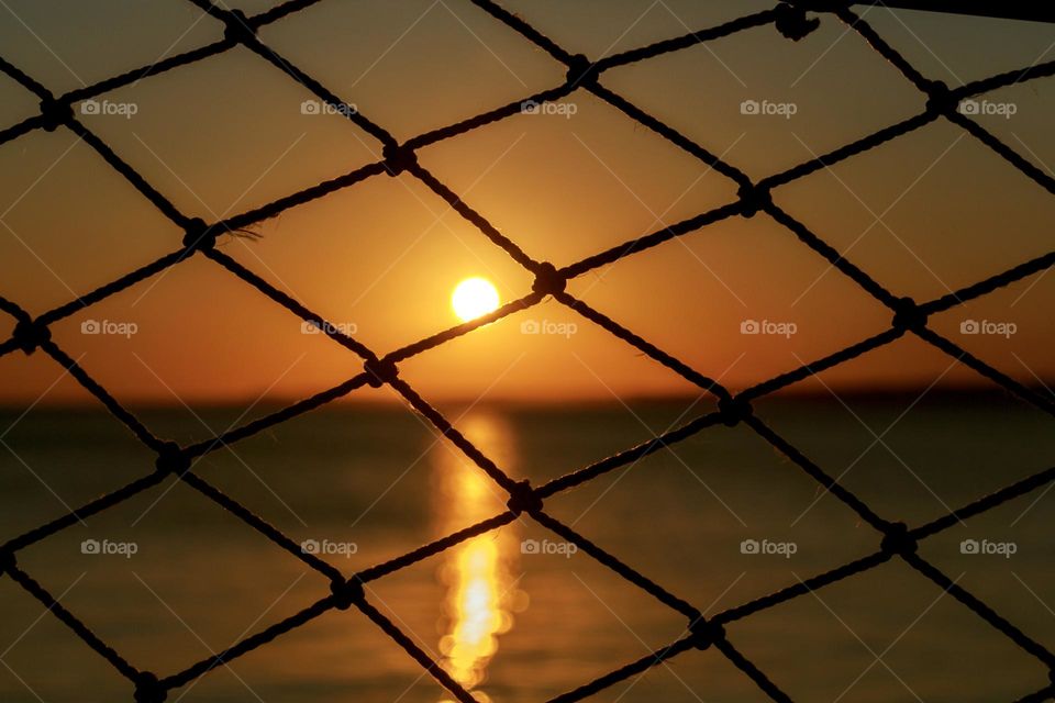 Beautiful sunset over the sea trough a net