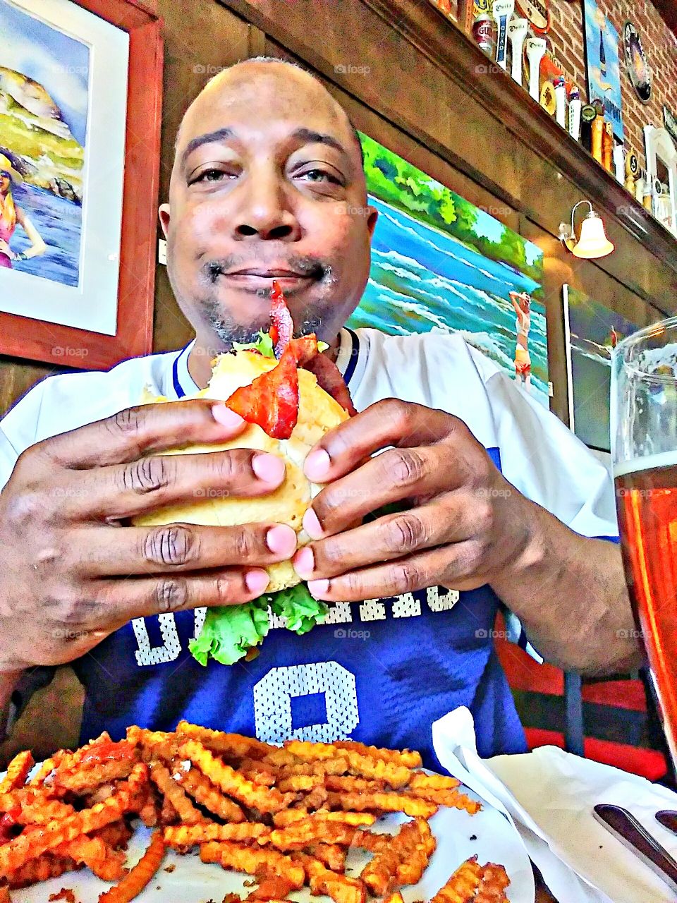 one of the best burgers in town in hand, a avocado bacon burger with onions lettuce and tomatoes