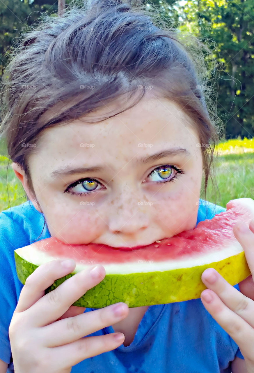 girl eating slice of juicy watermelon outdoors