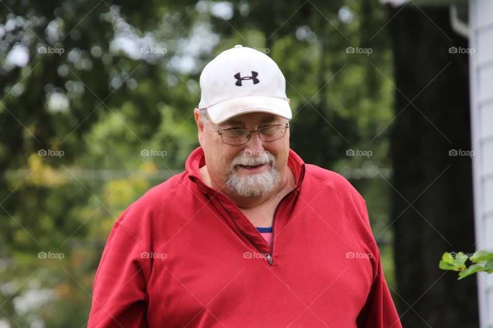 Man with facial hair wearing white hat and red shirt 