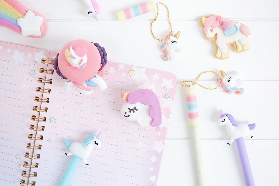 Unicorn stationery. Keeping diary with sweet unicorn pens and pencils with cute macarons and cookie. Little girl's diary. Day dreaming concept.