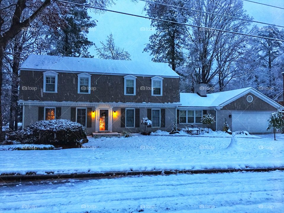 Home covered in snow with Christmas trees.