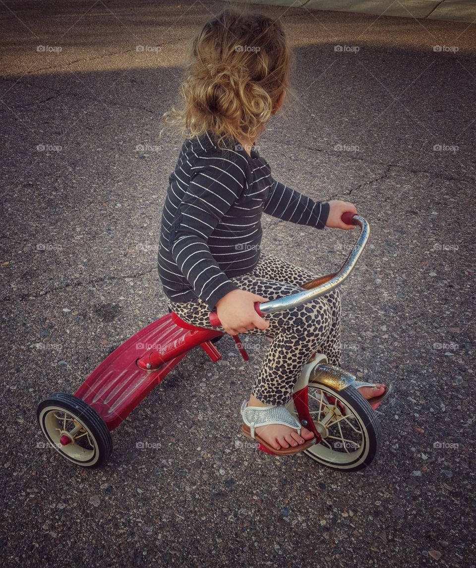 Little girl with tricycle on road