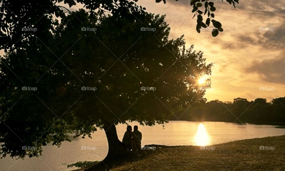 Silhouette of a couple under the tree by the river