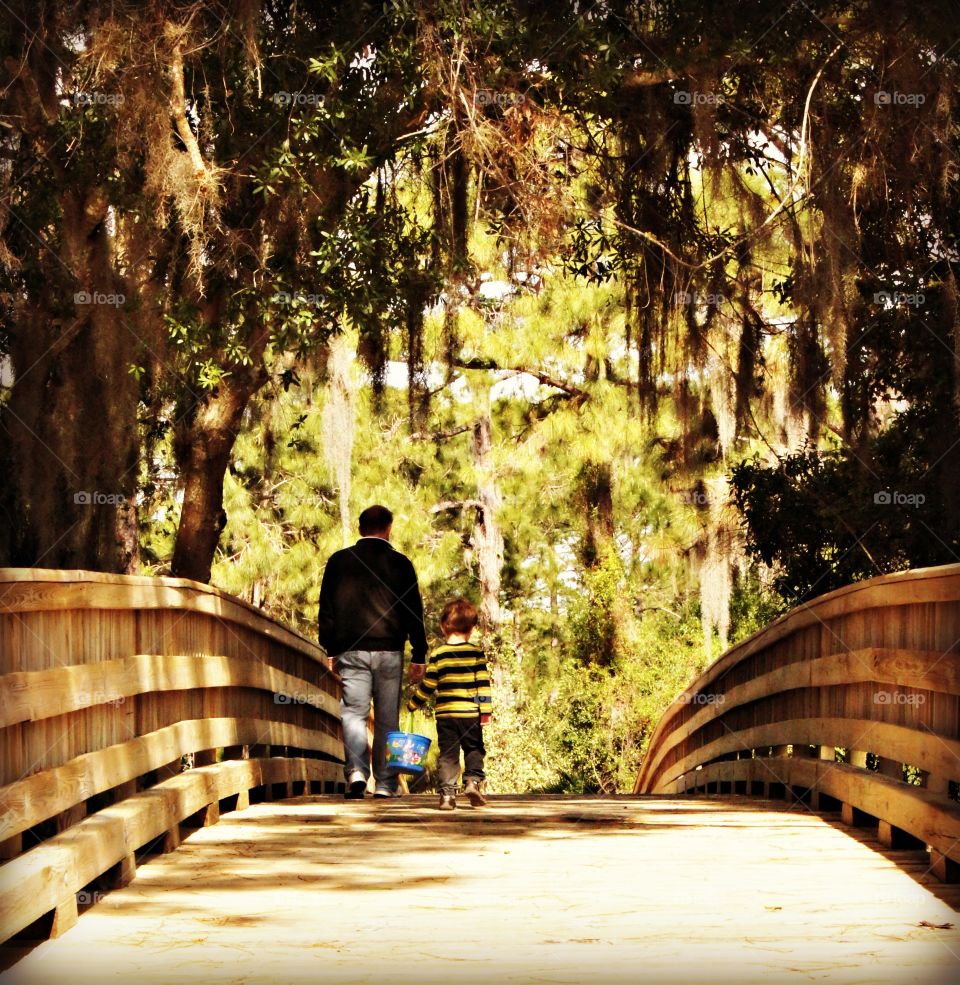 Rear view of man walking on footbridge with son