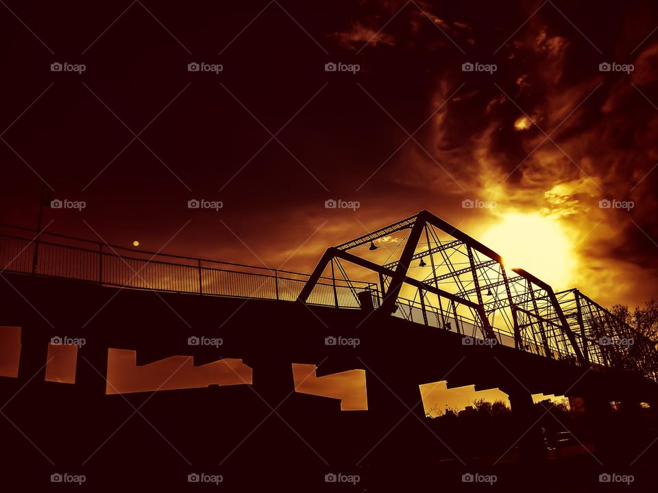 Creative photo -Old bridge silhouette with blazing sun and a dark sky.