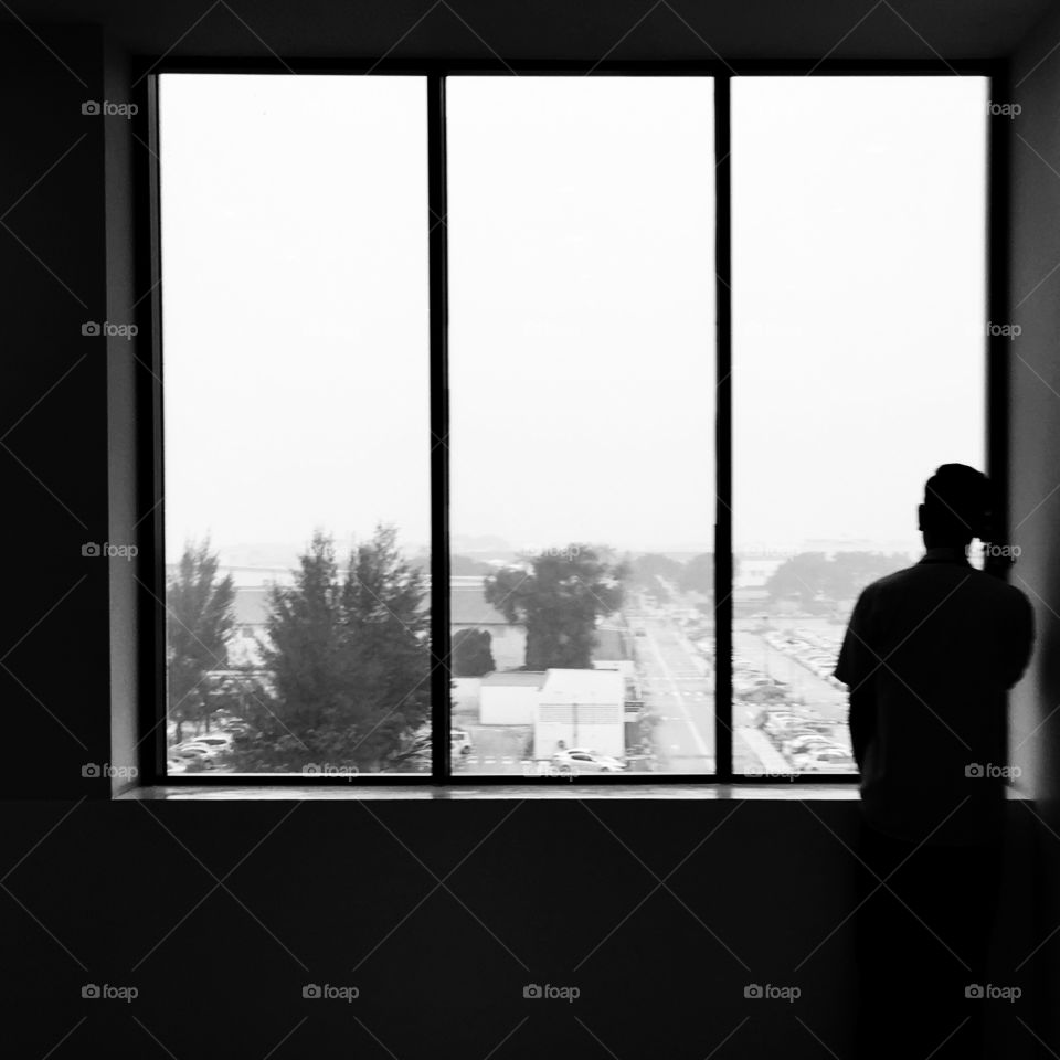 Haze Alert. A men standing by the glass window during the haze day.