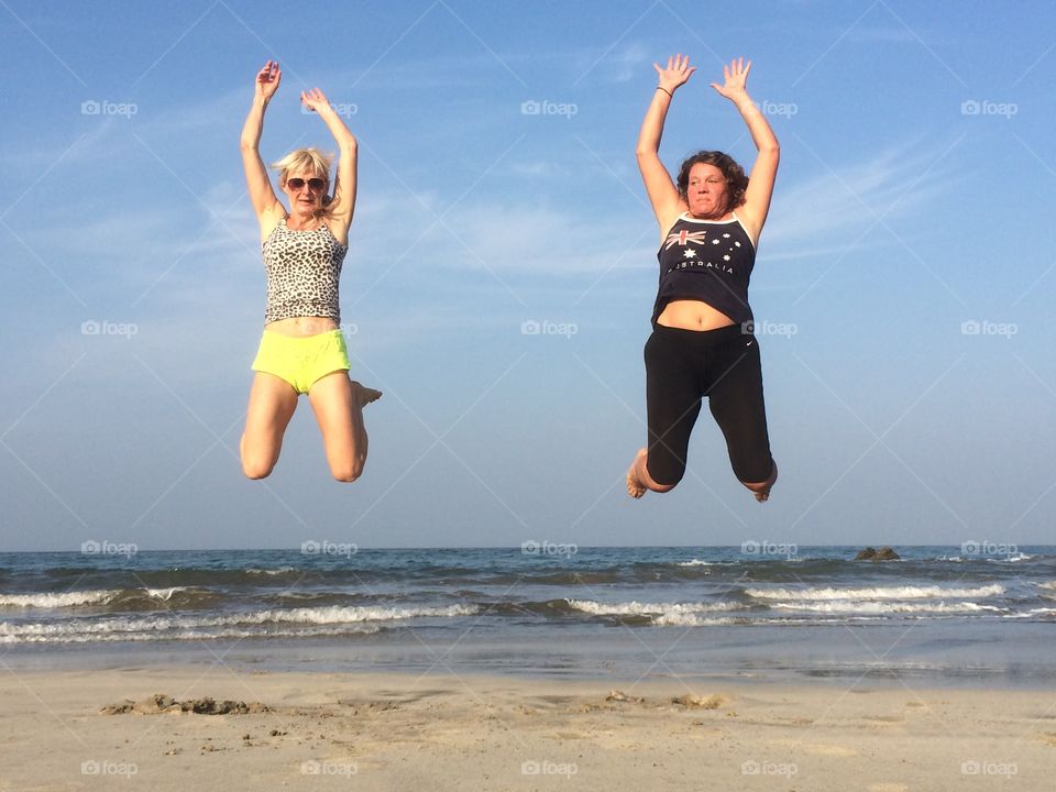 Two women jumping in the air at beach