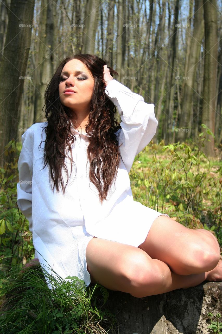 portrait of a beautiful girl in a white shirt in the forest