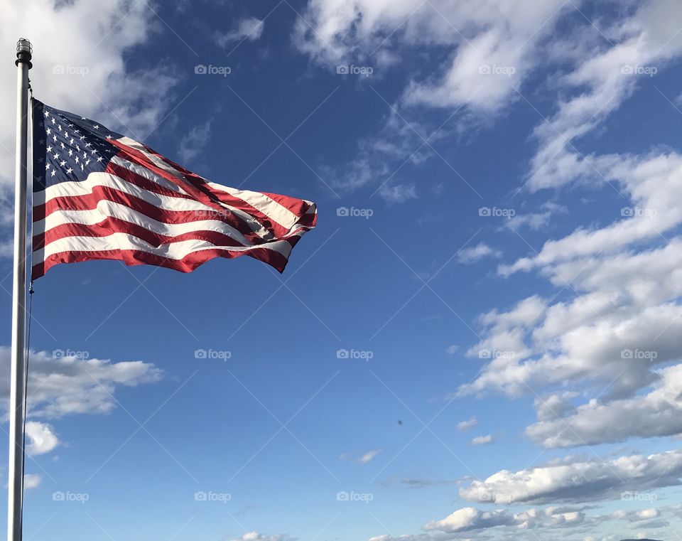 American Flag flying in a bright blue sky and slightly cloudy