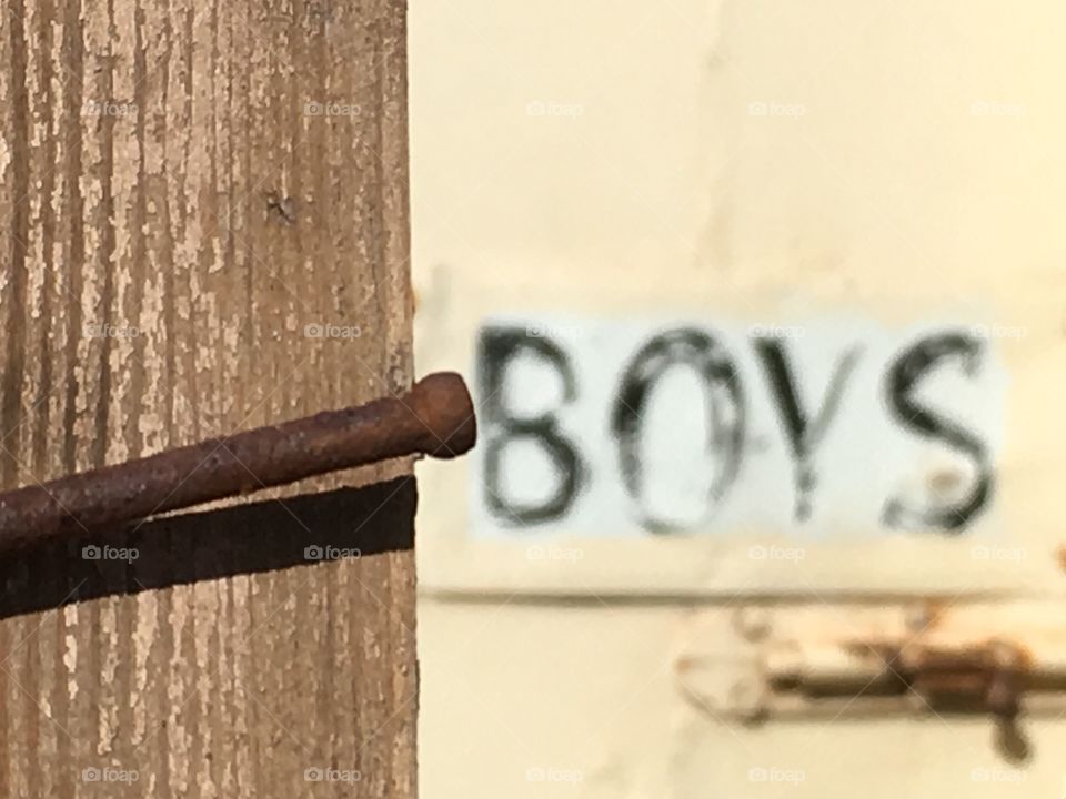 Rusted nail on weathered wood frame of old door on boys outhouse 