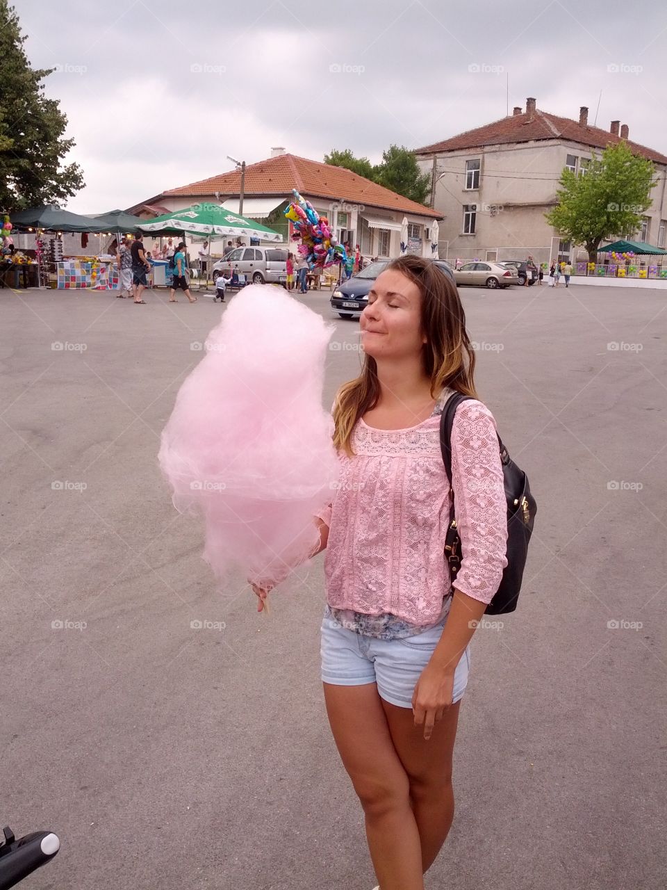 In this picture I am eating a pink big cotton candy at a fair in a small village in Bulgaria