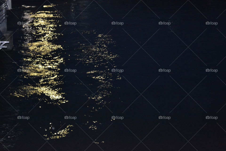 Dark water at night with light reflecting on the ripples