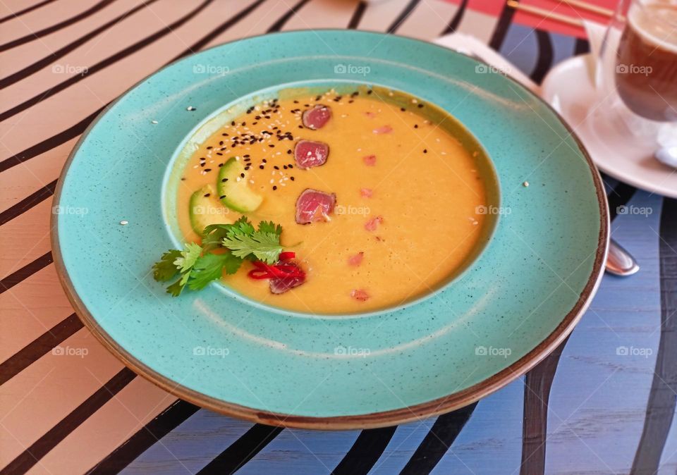 orange soup puree with tuna and salmon, very tasty, soup on the table, lunch, liquid soup