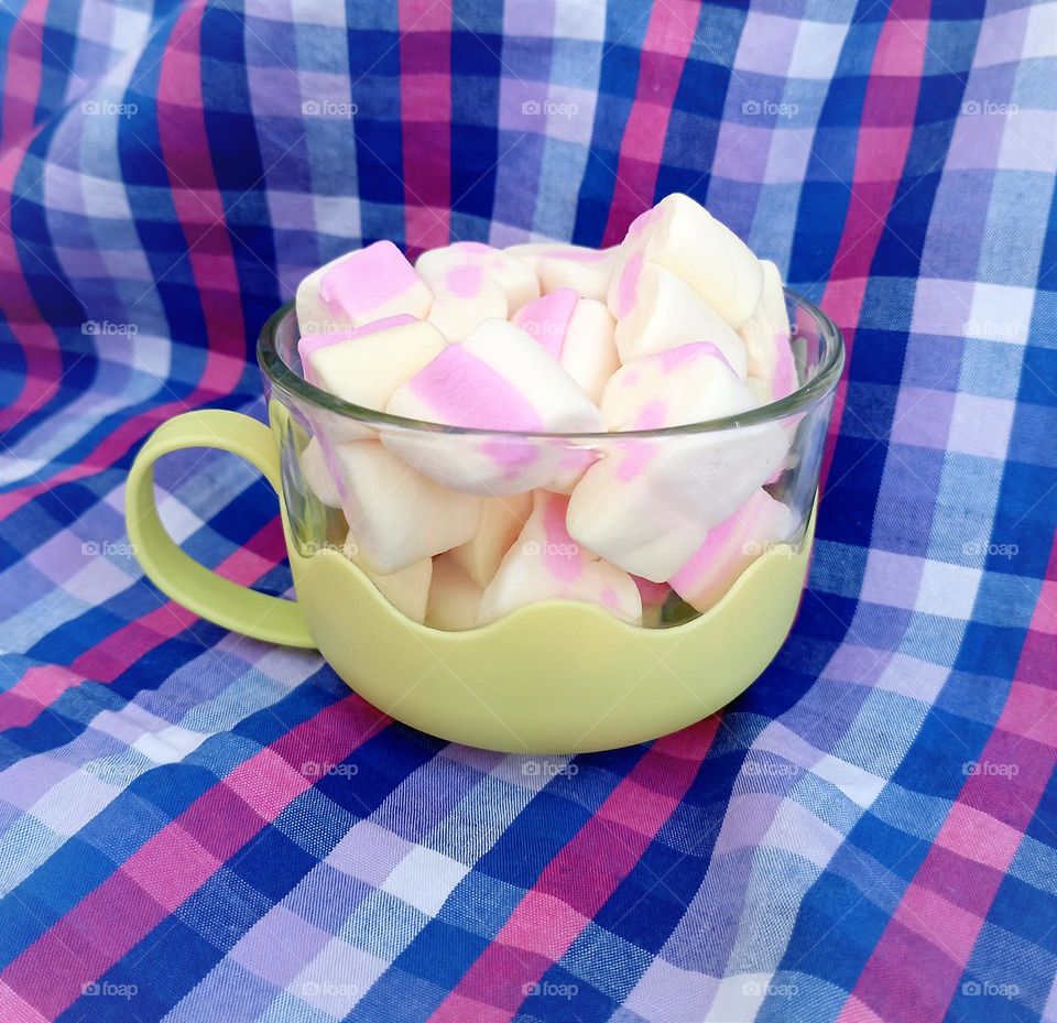 Marshmallows in a cup with table cover as the background...