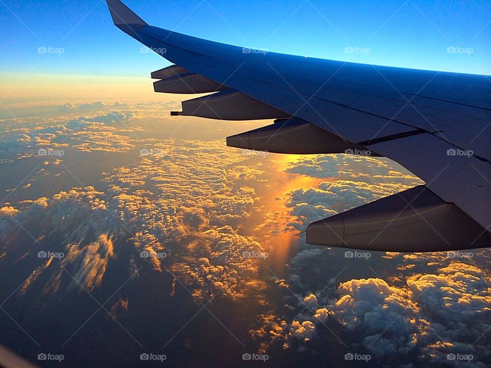 Plane over ocean reflecting sunset