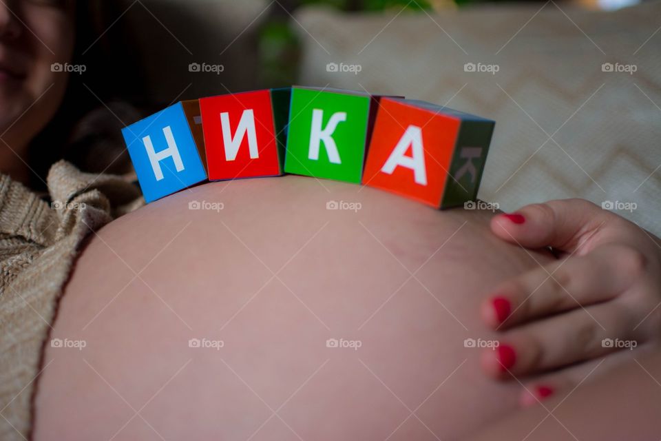 Toy cubes laying on a pregnant belly