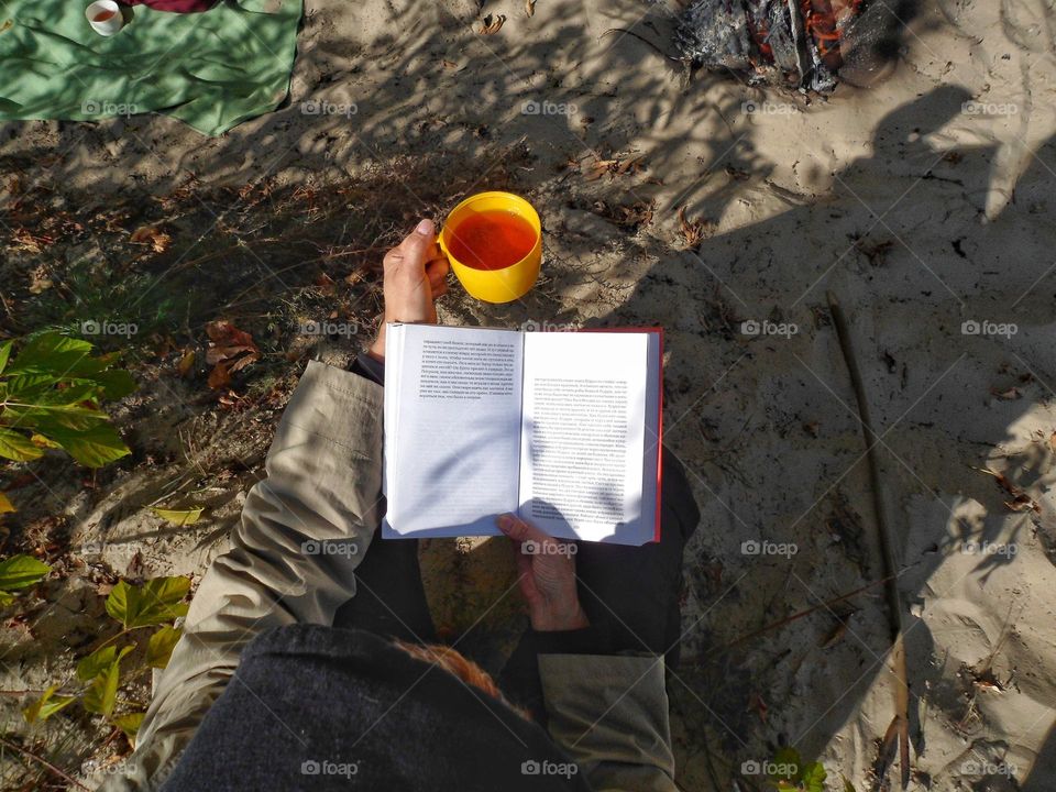 girl reading a book and drinking tea in nature