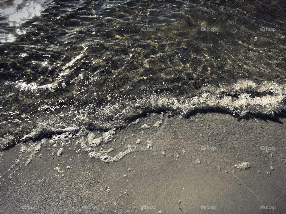 Rolling waves and sea foam on the beach.