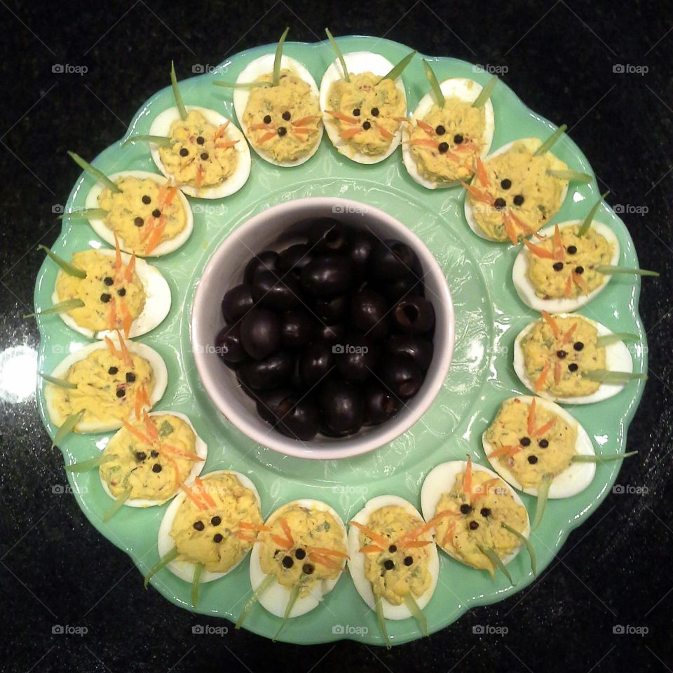 deviled eggs as easter bunnies on a jade green serving dish with black olives