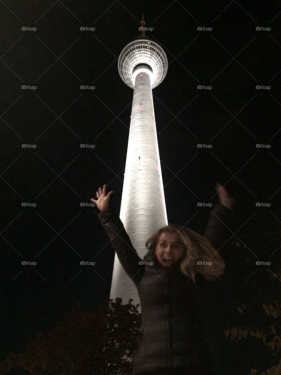 Woman jumping near television tower, Berlin at night
