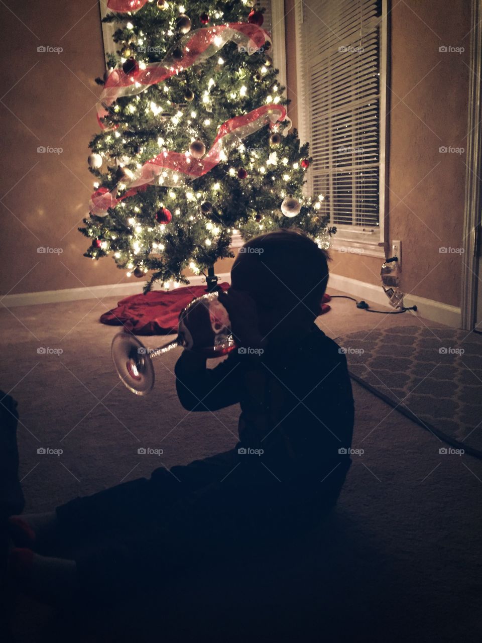 Silhouette of child drinking wine infront of christmas tree