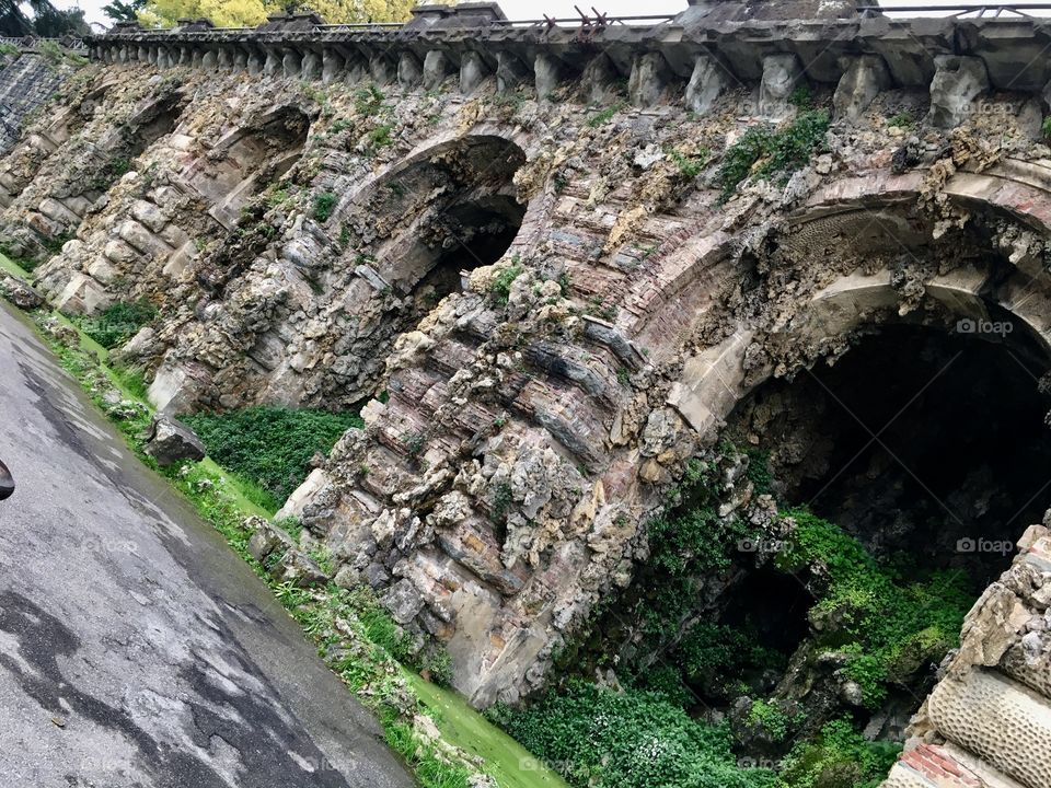 An unused antique bridge covered by moss and greenery.