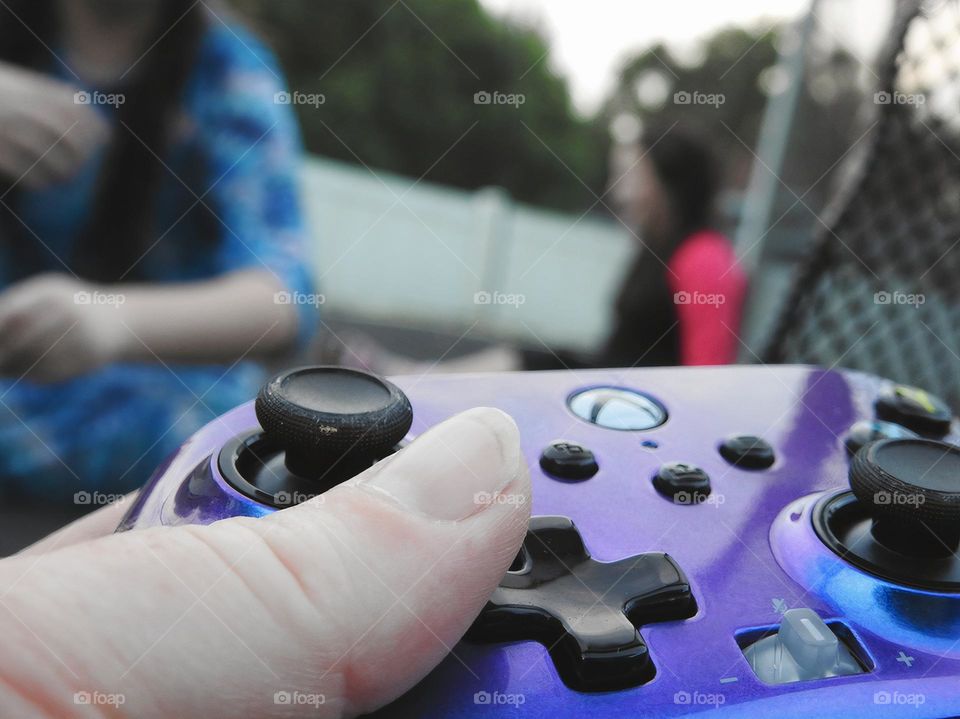 Xbox purple blue colored remote accessory used as if the mother is playing a game called: bring the children on the trampoline and play outside.