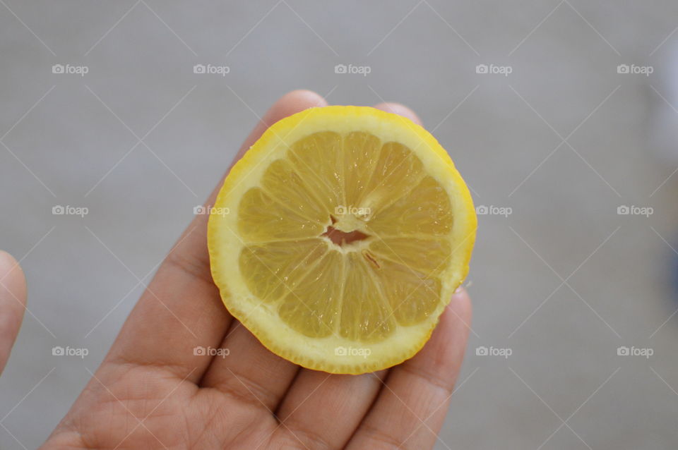 Hand holding slice of lemon