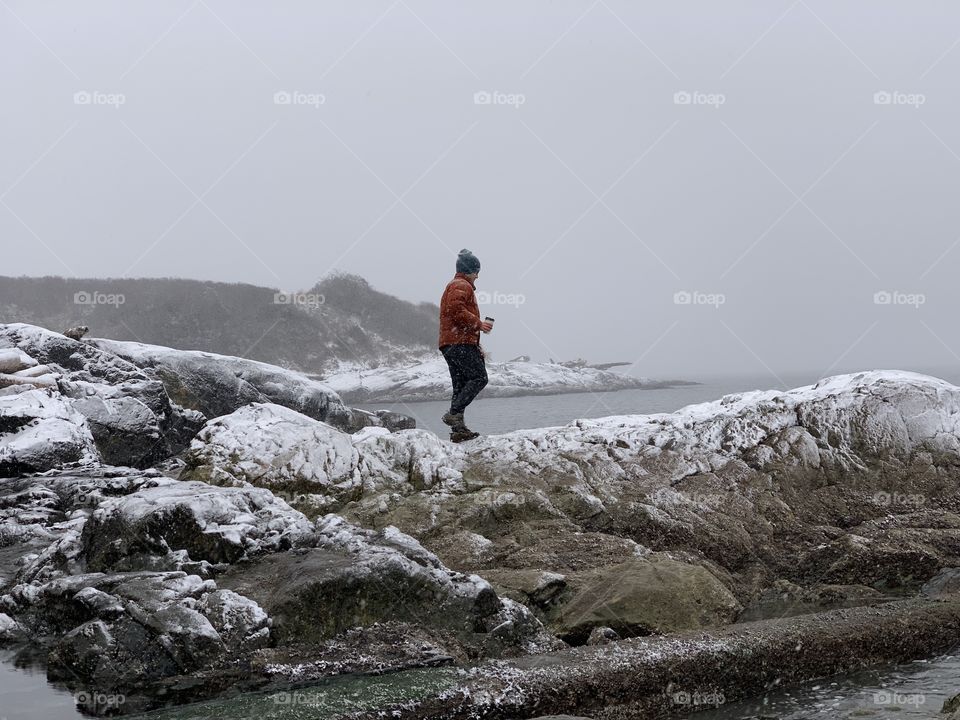 Man walking on a slippery rocks slightly covered with snow