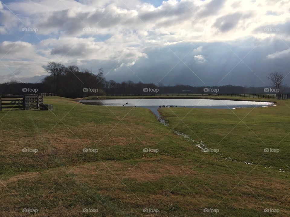 Pond at the end of the road with cool sky clouds and horizon 