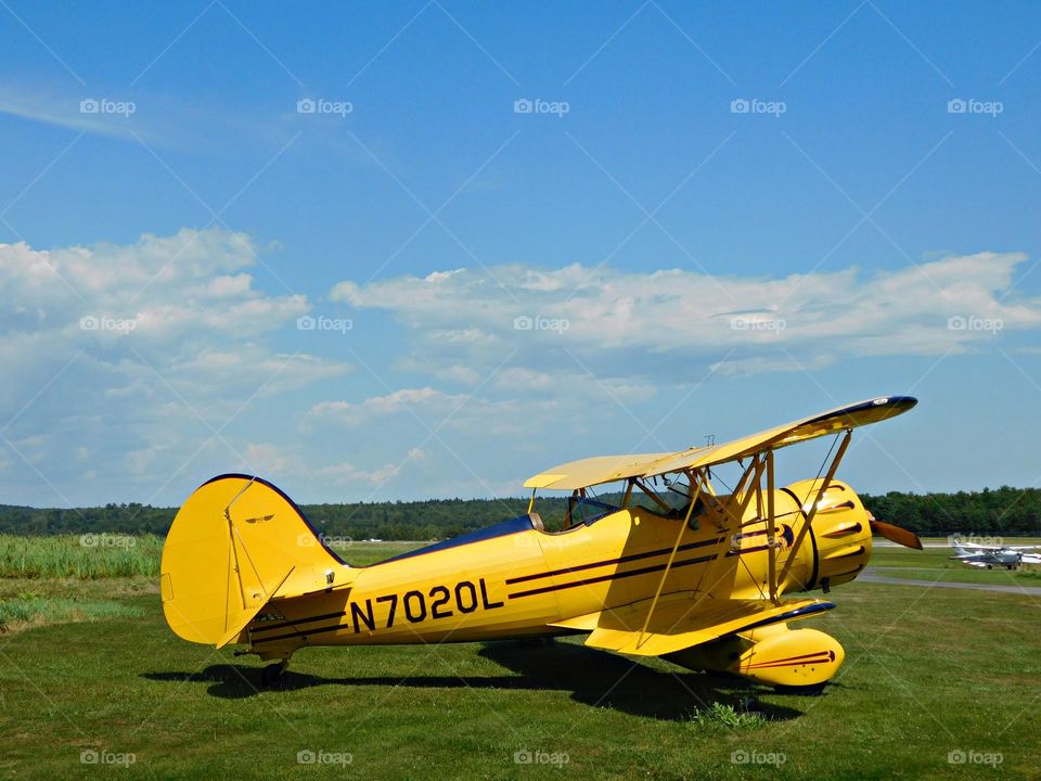 Bright yellow plane sitting on the grassy taxi way awaiting the next group of tourists for a local tour