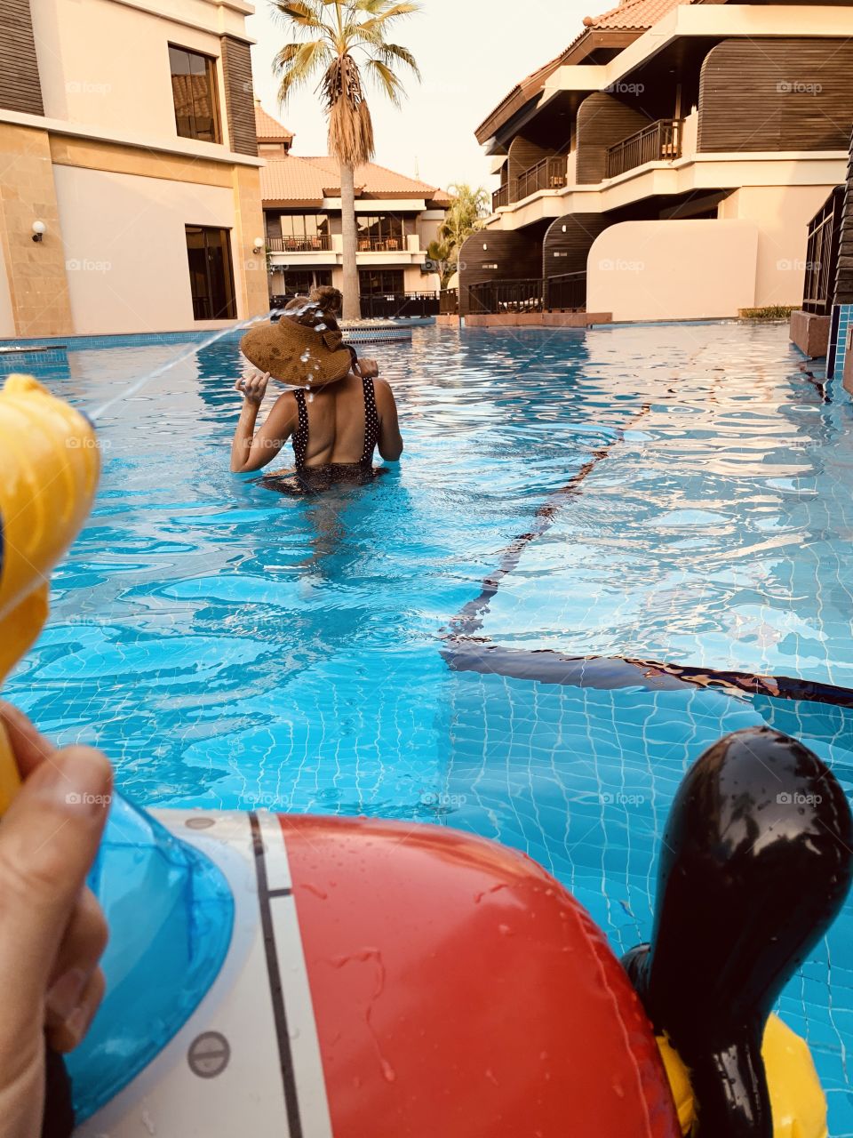 Family fun in pool , splash with water gun 