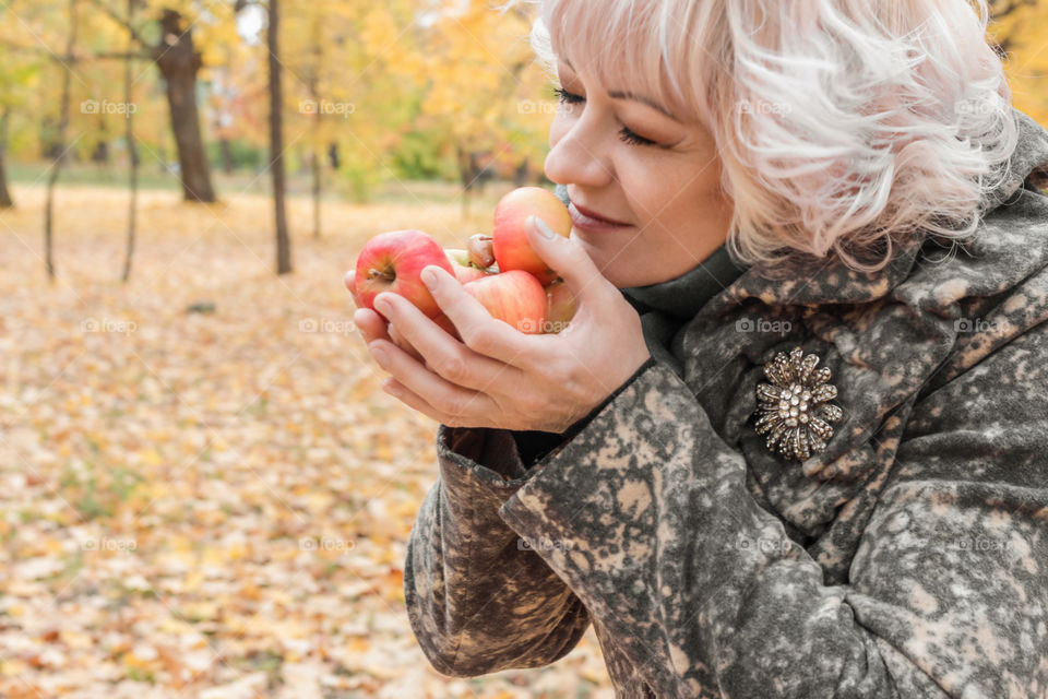 Autumn portrait of adult middle-aged woman in autumn clothes with apples