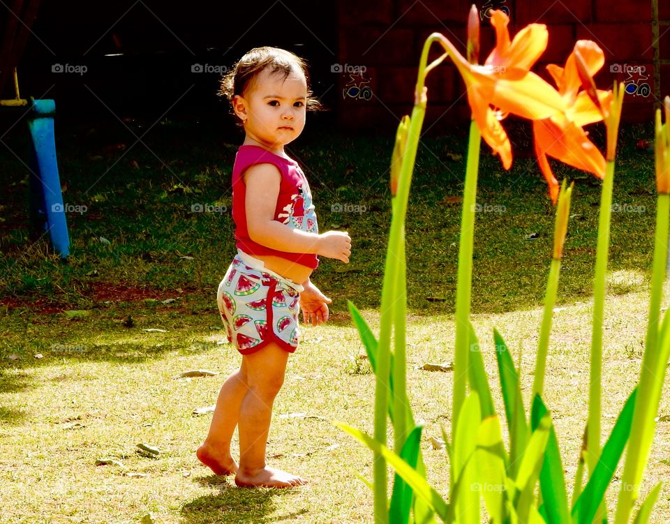 Cute girl standing in front of flower plant