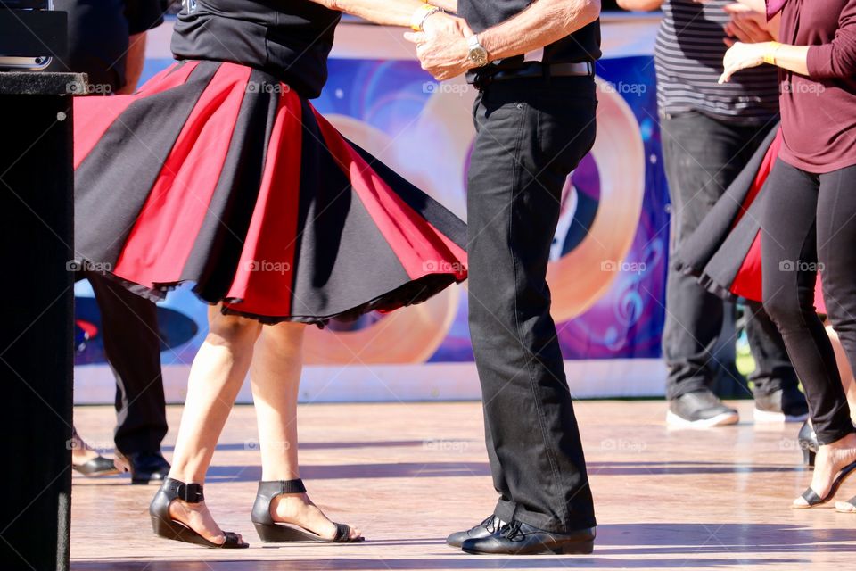 Couple in poodle skirts jiving rock and roll outdoor dancing festival waist down