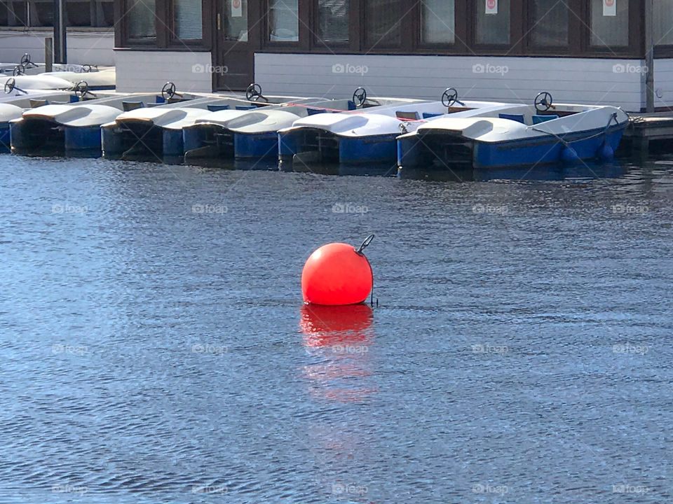 Orange ball in Alster lake and there are boats in the background