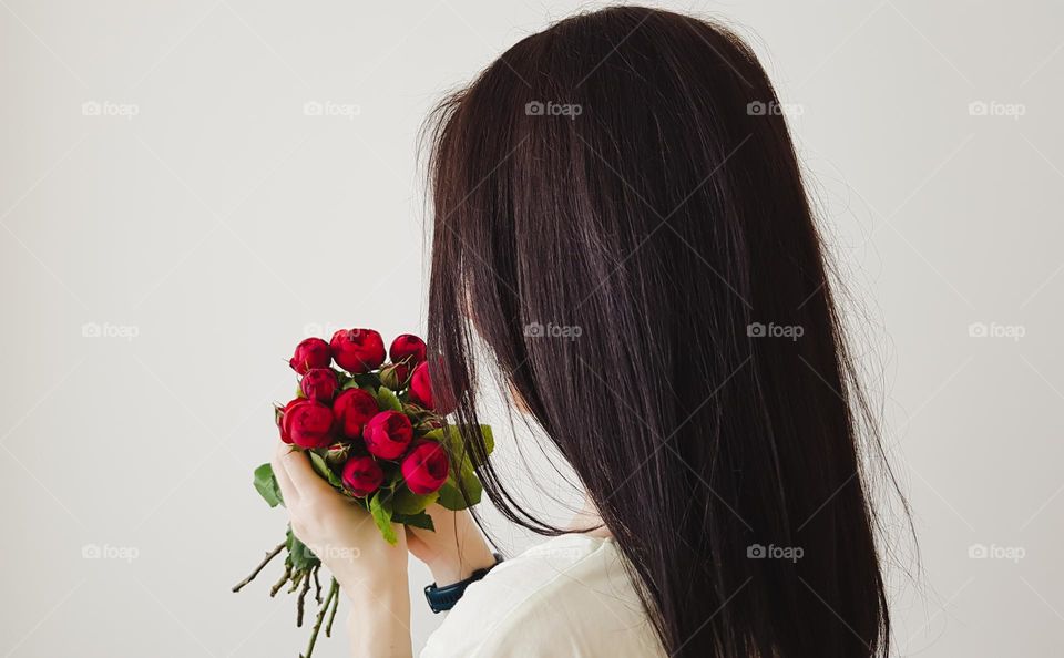 Young woman holding red flowers.