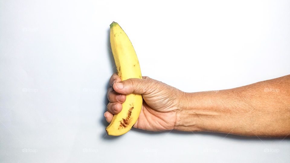 The hand is holding a banana in eye level view